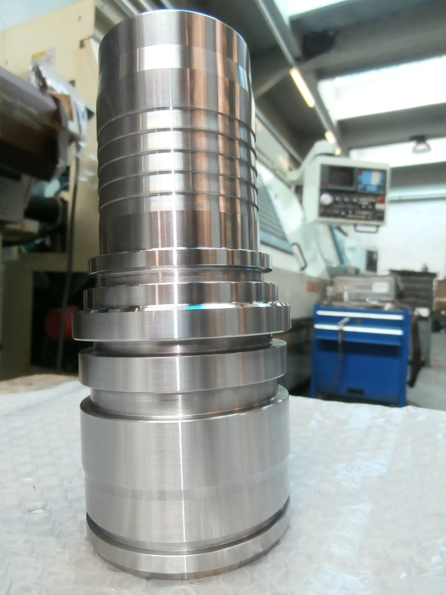 In primo piano un raccordo oleodinamico. Sullo sfondo un tornio CNC automatico "Biglia" da barra.